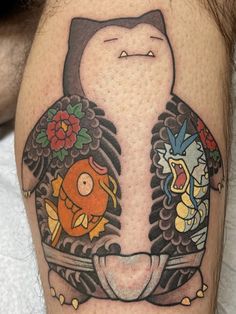 a tattoo on the leg of a man with an image of a cat and fish