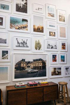 a wall full of pictures and photos with a wooden table in front of the photo