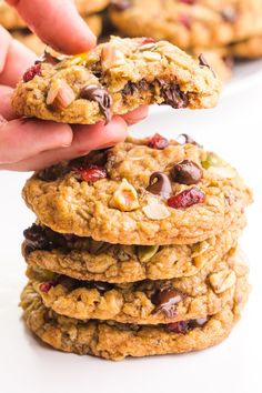 a hand picking up an oatmeal chocolate chip cookie from a stack of cookies