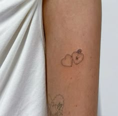 a woman's arm with a tattoo on it that has two hearts and an apple