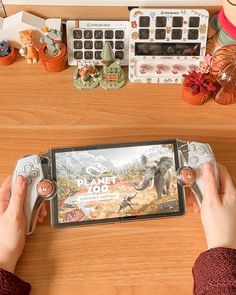 a person holding a nintendo wii game controller in front of a desk with various items on it