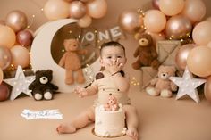 a baby sitting in front of a cake surrounded by balloons