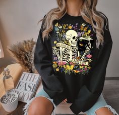 My shirts, sweatshirts, and tanks are a fun and joyous way to show your style while shopping, heading to the beach, and bringing your children to social events, family outings, and everyday life. All my t-shirt designs are direct to garment and provide the best quality and longevity.  It's a good day to read a book   Picture: Floral skeleton with book Sizes: S - 2XL  Fabric: Varies depending on color.  T-shirt Solid colors are 100% cotton T-shirt Heather colors are 52% cotton and 48% Polyester Sweatshirt colors are 50% cotton and 50% polyester  Tank Colors are 60% cotton and 40% polyester  The product materials I have chosen are excellent quality, soft, comfortable, and fit true to size. I have also provided in the product images how to order if you are looking for an oversized look. I hon Fall Bookish Tops With Graphic Print, Fall Graphic Print Bookish Tops, Black Relaxed Fit Tops With Bookish Style, Floral Skeleton, Converse Shirt, Bookish Merch, Family Outings, It's A Good Day, Botanical Shirt