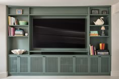 a large flat screen tv sitting on top of a green book shelf next to a wall