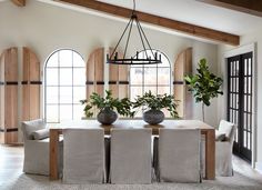 a dining room table with chairs and potted plants on top of it in front of arched windows