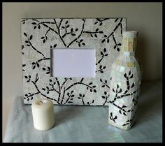 a white vase sitting on top of a table next to a photo frame and candle