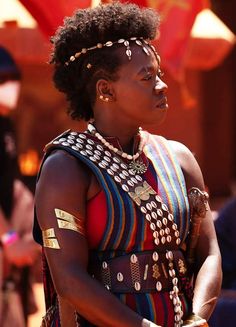 a woman in an elaborately decorated dress and headpieces looks off to the side