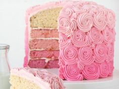 a cake with pink frosting is cut into pieces and sits next to a glass of milk