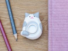 a pencil holder with a cat on it next to two pens and a rubber eraser