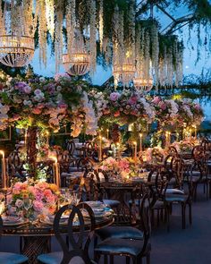 an outdoor dining area with chandeliers and flowers