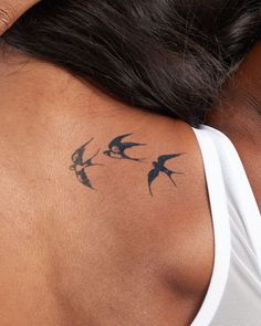 a woman's back with birds tattoo on her left shoulder and right arm behind her neck