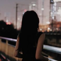 a woman standing in front of a cityscape with her back to the camera