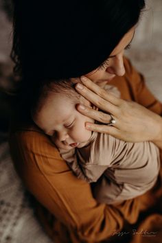 a woman holding a baby in her arms while she is wearing a ring on her finger