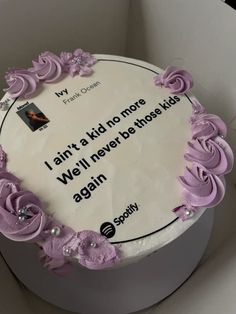 a white cake with purple frosting and flowers on it's side in a box