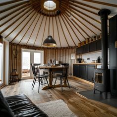 a living room and dining area with wood flooring in a yurt style home