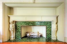 a fireplace with green tiles and statues on the mantle