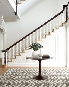 a table with two vases sitting on top of it next to a stair case