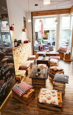 a room filled with lots of wooden tables and chairs next to a chalkboard wall