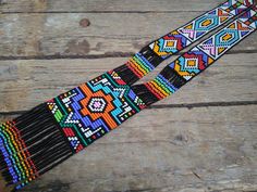 two multicolored beaded necklaces sitting on top of a wooden table next to each other