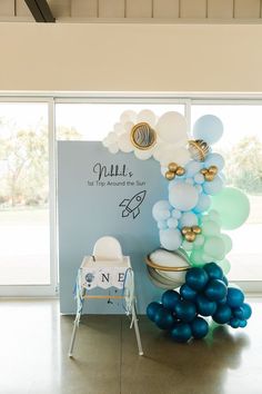 balloons are arranged in front of a sign and chair