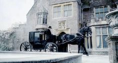 a horse drawn carriage parked in front of a large brick building on a snowy day