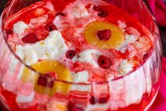 a dessert in a glass bowl with fruit and cream toppings on top, ready to be eaten