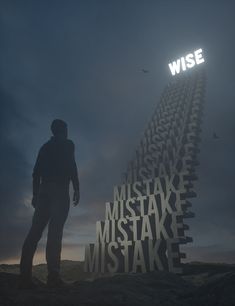 a man standing on top of a hill next to a tall tower with words written in it