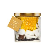 a glass jar filled with marshmallows and brownies next to a gold label