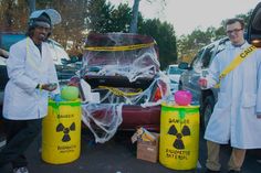 two men in lab coats standing next to trash cans