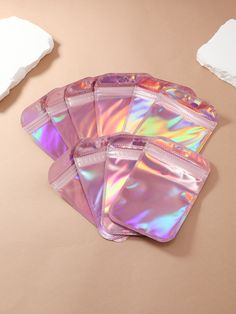 five holographic pouches sitting on top of a table next to a piece of paper