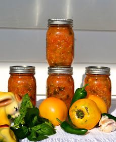 several jars filled with food sitting on top of a white table next to some vegetables