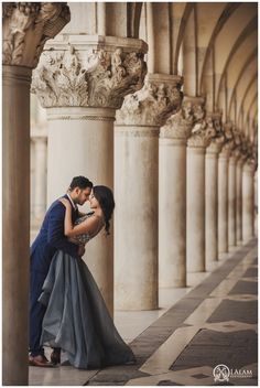 a man and woman standing next to each other in front of some tall pillars with columns