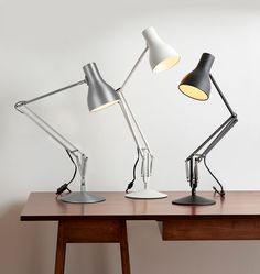 two desk lamps sitting on top of a wooden table