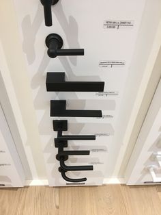 an assortment of black handles on a white wall in a room with wood flooring