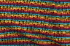 a multicolored knitted blanket is shown in close up, with stripes on it