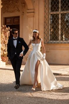 a man and woman in formal wear walking down the street with one foot on the ground