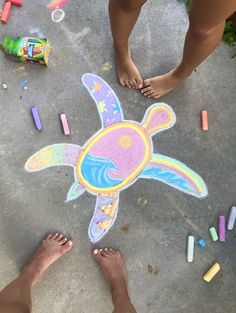 two people standing next to a chalk drawing turtle