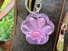 a pink flower shaped keychain hanging from a purse