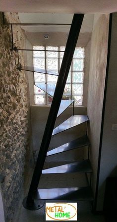 there is a metal staircase going up to the second floor in this house with stone walls and windows