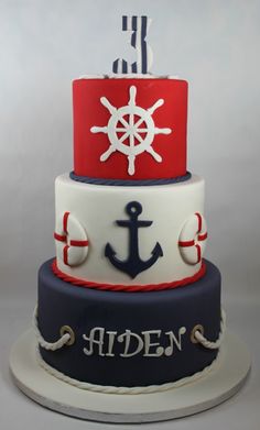 a three tiered cake with an anchor and helm on top