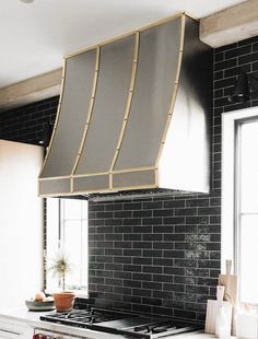 a stove top oven sitting inside of a kitchen under a metal hood over a sink