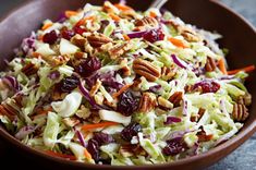 a wooden bowl filled with coleslaw and pecans