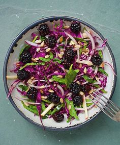 a white bowl filled with lots of food on top of a green tablecloth next to a fork