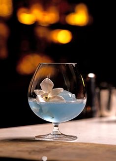 a glass filled with water and flowers on top of a table