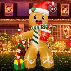 an inflatable gingerbread man holding a cup and candy cane with christmas lights behind it