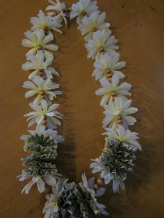 white flowers and pine cones are arranged in the shape of an oar on a wooden table