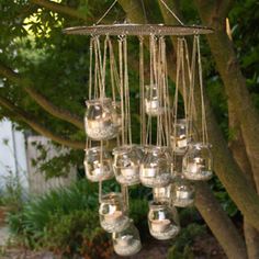 a chandelier hanging from a tree with wine glasses in front of it on a table