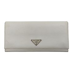 DESCRIPTION (Features and defects) : Saffiano long women's wallet in white leather.Metal logo applied on the front.Flap closure with two snap buttons.With three main compartments and multi card pockets.Black nylon interior.It has small scratches and discolorations on the corners, but its overall condition is very good.DIMENSIONS: W: 19cm - H: 9cm Prada Saffiano, Prada Wallet, Handbag Wallet, Moda Vintage, Wallet Accessories, Metal Logo, Diaper Backpack, Black Nylon, Mode Vintage