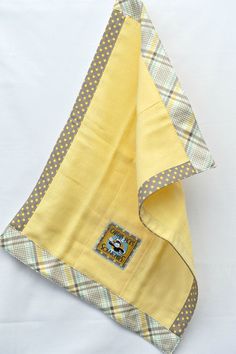 a yellow and gray blanket laying on top of a white sheet