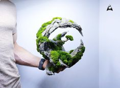 a man holding a piece of art made out of rocks and moss in his hand